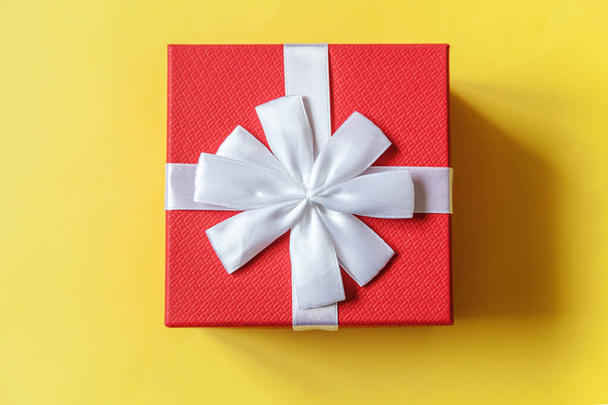 Weihnachten Silvester Geburtstag valentine Feier präsentieren romantisches Konzept. Einfach minimalistisches Design rote Geschenkbox auf gelbem Hintergrund isoliert. Flache Lageansicht Kopierraum - Foto, Bild