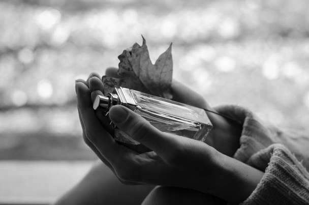 Czarno-białe zdjęcie butelki perfum w rękach kobiet - Zdjęcie, obraz