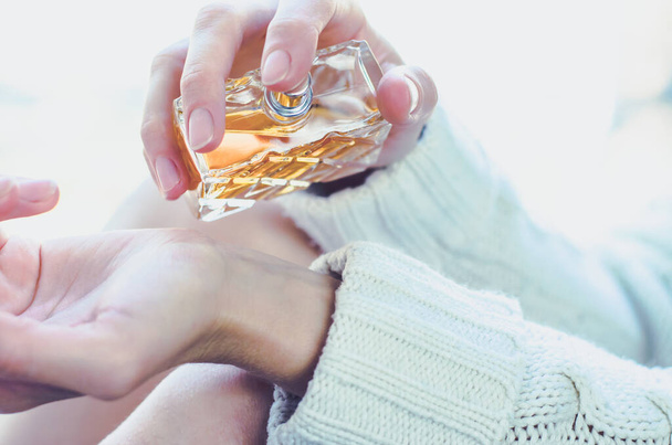Młoda kobieta posypuje nadgarstek perfumami. Perfumy w kobiecej dłoni - Zdjęcie, obraz