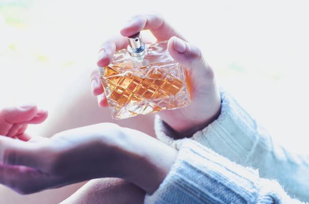 Junge Frau streut Parfüm über ihr Handgelenk. Parfüm in der Hand einer Frau - Foto, Bild