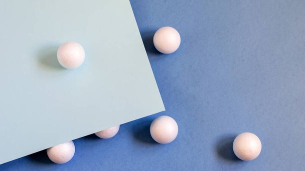 White balls on the blue paper background. Nice idea for trendy design. Top view, flat lay photo.  - Foto, Imagem