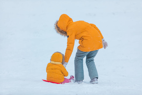 мать с дочерью скольжения от снежного холма зимний сезон - Фото, изображение