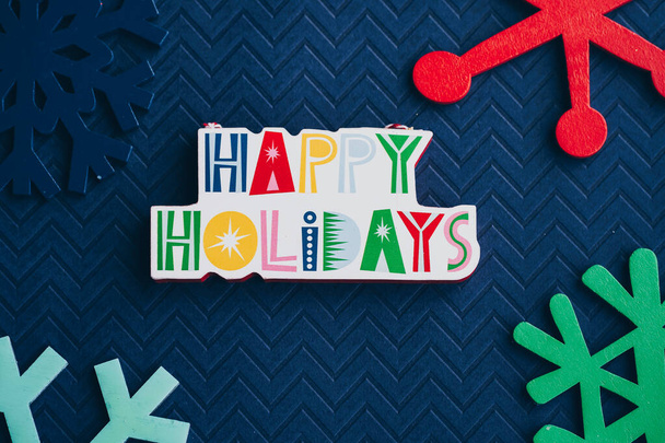 Happy Holidays messaggio placca e colorato fiocchi di neve in legno su sfondo blu, per i progetti di Natale - Foto, immagini