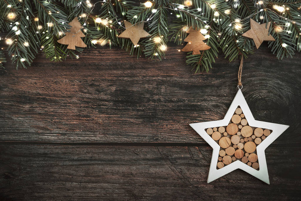 Καλά Χριστούγεννα. Χριστούγεννα έννοια φόντο.Χριστουγεννιάτικο δέντρο κλαδιά με χριστουγεννιάτικα φώτα και χριστουγεννιάτικο αστέρι στο τραπέζι από ξύλο - Φωτογραφία, εικόνα