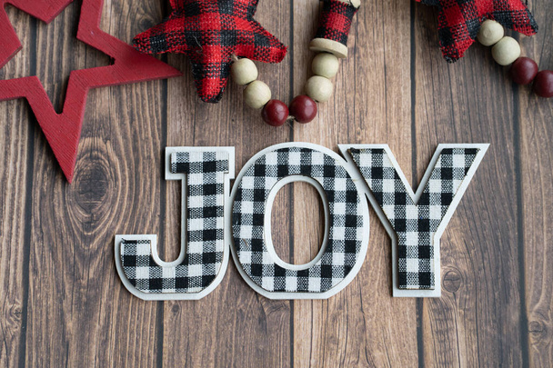 Black and white joy plaid phrase on a wood background with red stars, useful for Christmas projects - Foto, immagini