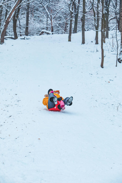 father with daughter in yellow winter coats sliding snowed hill family time - Photo, Image