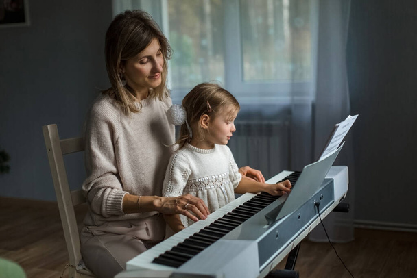 Studying music, mom and daughter are studying synthesizer. Keyboard game. Music lessons - Foto, Imagem
