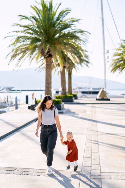 Mom and daughter are running and having fun on a boat pier by the sea - Photo, Image