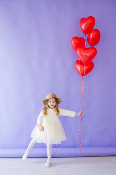 Όμορφο κοριτσάκι κρατώντας κόκκινα μπαλόνια για τις διακοπές - Φωτογραφία, εικόνα