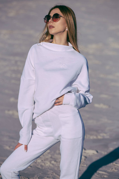 Mujer de moda con ropa blanca y abrigada al aire libre en la playa - Foto, imagen
