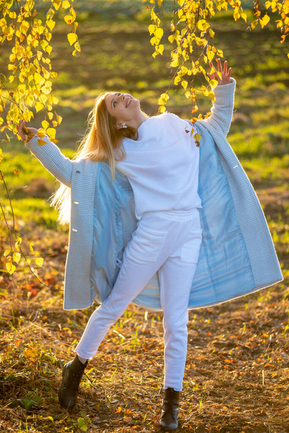 Beautiful woman in autumn clothes outdoor, blue sky background - 写真・画像