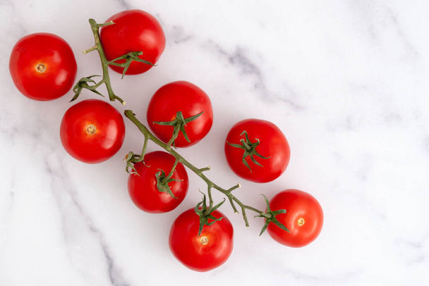 Red tomatoes close up on marble background, flat lay with copy space - 写真・画像