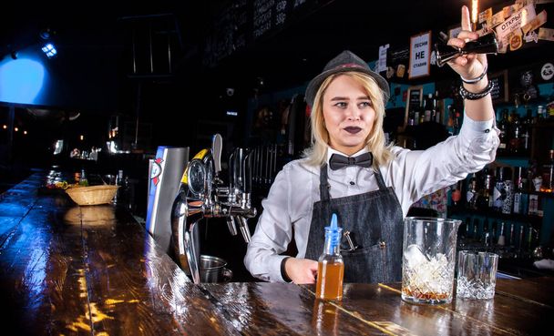 Charming woman barkeeper is pouring a drink behind the bar - Photo, Image