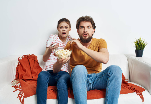 Paar verliefd op popcorn en tv kijken terwijl op de bank binnen - Foto, afbeelding