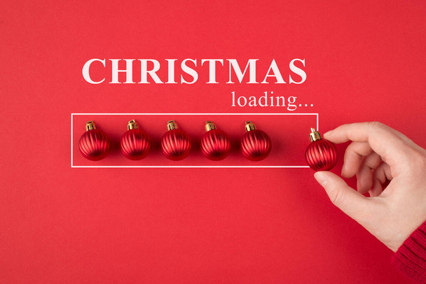 Waiting for the holiday concept. Cropped closeup top view photo of hand holding small toy tree ball putting in a line isolated over bright red color background - Photo, Image