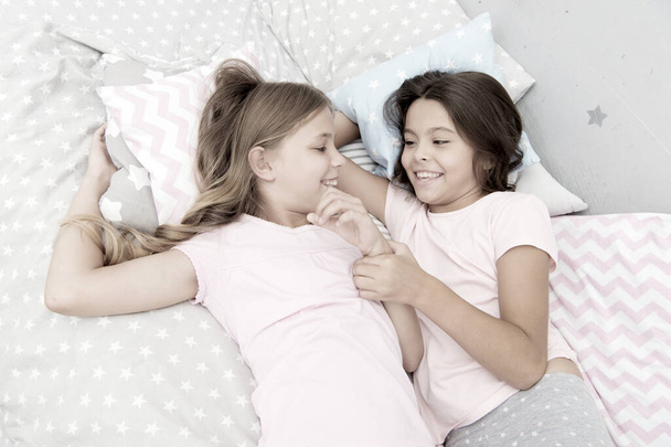 Sisters happy small kids relaxing in bedroom. Friendship of small girls. Leisure and fun. Having fun with best friend. Children playful cheerful mood having fun together. Pajama party and friendship - Foto, Bild