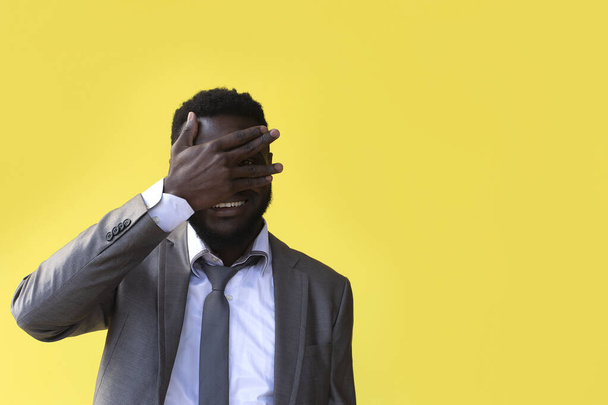 zblízka nespokojený afro Američan s rukou na hlavě bafání ve studiu žluté pozadí - Fotografie, Obrázek