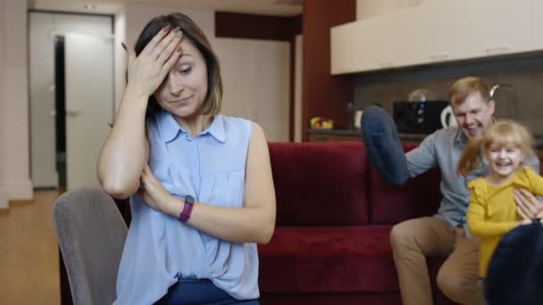 Müde depressive junge kaukasische Mutter fühlt sich sehr genervt von aktivem Vater und Tochter - Filmmaterial, Video