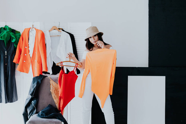 Woman choosing outfit from large wardrobe closet with stylish clothes and home stuff - 写真・画像