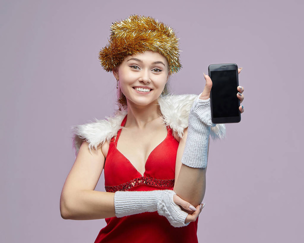 beautiful young woman in Santa costume shows off smartphone - Фото, зображення