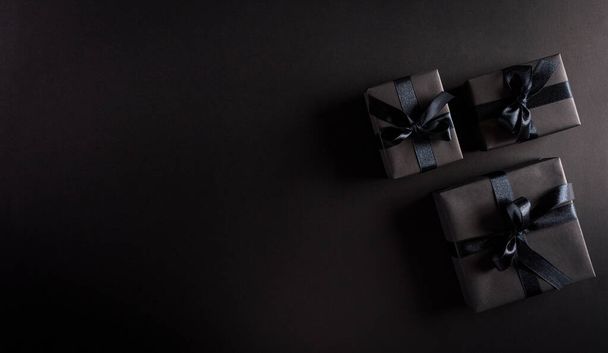 Top view fekete karácsonyi ajándékdobozok fekete szalaggal fekete háttér másolási hely szöveg. Fekete péntek kompozíció. - Fotó, kép