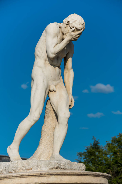 Kain Statua w Tuileries Garden w Paryżu, jeden z wielu posągów w Tuileries Garden. Pokazuje nagiego mężczyznę stojącego lub podpartego niezręcznie prawą ręką zakrywającą twarz..  - Zdjęcie, obraz