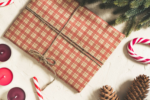 Christmas gift wrapped in checkered craft paper with candles and decorations on a rough surface, with a copy space - Photo, image