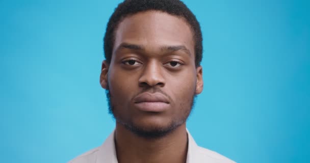 close-up portret van serieus eens Afrikaans amerikaanse man knikken hoofd over blauw studio achtergrond - Video