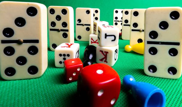 Composition on green background of board games, dice, dominoes, cards and ludo. - Photo, Image