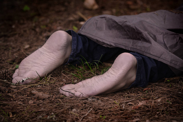 Um cadáver descalço na floresta. Vítima de homicídio deitada no chão na floresta. Cidadão assassinado, cena do crime - Foto, Imagem