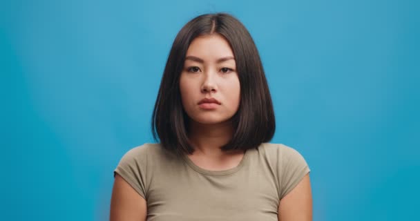 Mujer asiática joven enferma que sopla la nariz en el tejido, tiene resfriado estacional o reacción alérgica, fondo azul del estudio - Imágenes, Vídeo