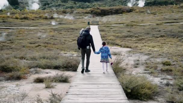 Craters of The Moon Geysers Park, Nueva Zelanda. Padre e hija caminando por el sendero con vapor del valle geotérmico. Movimiento lento - Imágenes, Vídeo