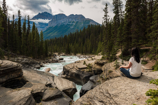 Frau sitzt auf Felsen und entspannt sich im Mistaya Canyon im Jasper Nationalpark, Alberta, Kanada. - Foto, Bild