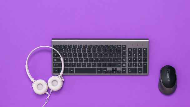 Draadloos toetsenbord, muis en witte hoofdtelefoon op een paarse achtergrond. Het uitzicht vanaf de top. - Foto, afbeelding