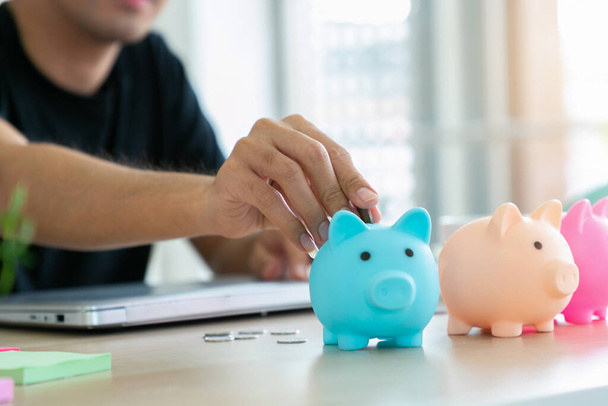 Close up hand of man putting money coin into piggy for saving money wealth and financial concept. - Foto, Imagem