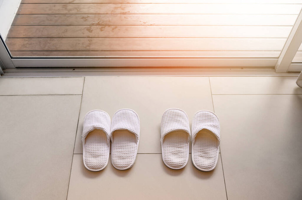 Vista superior de zapatillas blancas por cortinas blancas y luz solar suave, concepto de vacaciones - Foto, Imagen