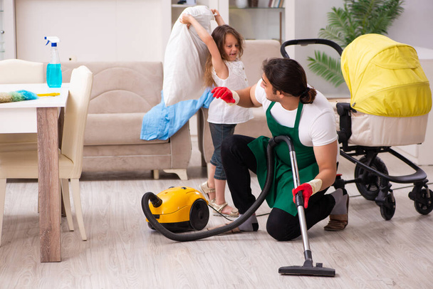 Joven contratista masculino limpiando la casa con su hija pequeña - Foto, imagen
