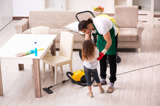 Νεαρός εργολήπτης καθαρίζει το σπίτι με τη μικρή του κόρη. - Φωτογραφία, εικόνα