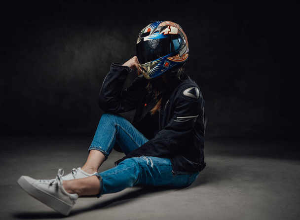 Wearing helmet female motorcyclist in dark background - Valokuva, kuva