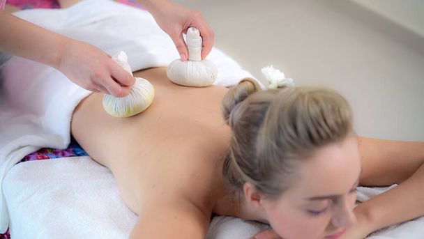 Massage therapist using herbal compress with woman - Photo, image