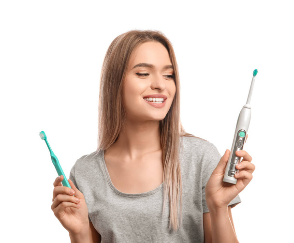 Young woman with different tooth brushes on white background - Photo, Image