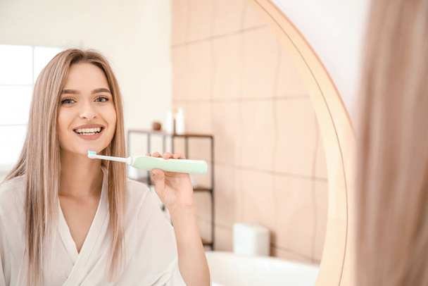 Mujer joven cepillándose los dientes en el baño - Foto, Imagen
