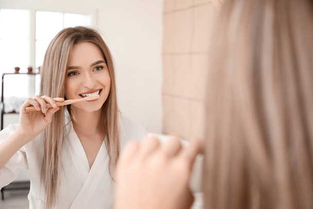 Jeune femme brossant les dents dans la salle de bain - Photo, image