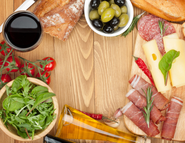 Красное вино с сыром, оливками, помидорами, прошутто, хлебом и специями
 - Фото, изображение