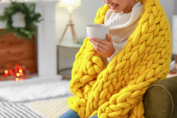 Красивая молодая женщина с теплым клетчатым чаем дома - Фото, изображение