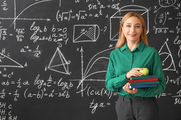 Volwassen wiskunde leraar in de buurt van schoolbord in de klas - Foto, afbeelding