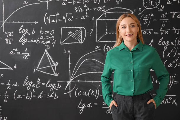 Зрелая учительница математики возле классной доски - Фото, изображение