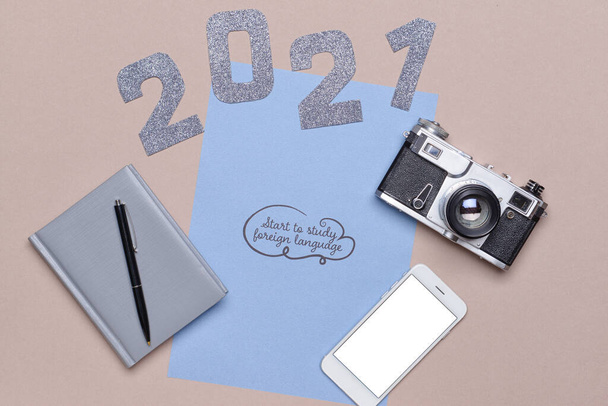Φύλλο χαρτιού με κείμενο START TO STUDY FOREIGN LANGUAGE, σχήμα 2021, κινητό τηλέφωνο και φωτογραφική μηχανή σε γκρι φόντο - Φωτογραφία, εικόνα