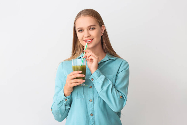 Young woman with wheatgrass juice on light background - Photo, Image