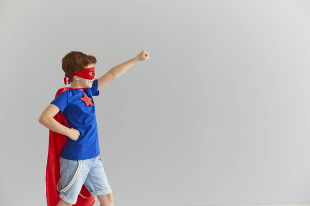 Little smiling boy in a superhero costume with a red cloak and glasses is ready for adventure. - Fotoğraf, Görsel